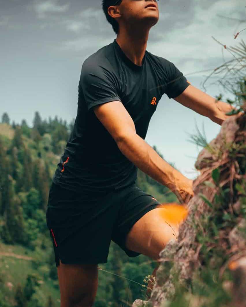 A trail running climbing up a mountain and wearing and head to toe Revario running outfit.